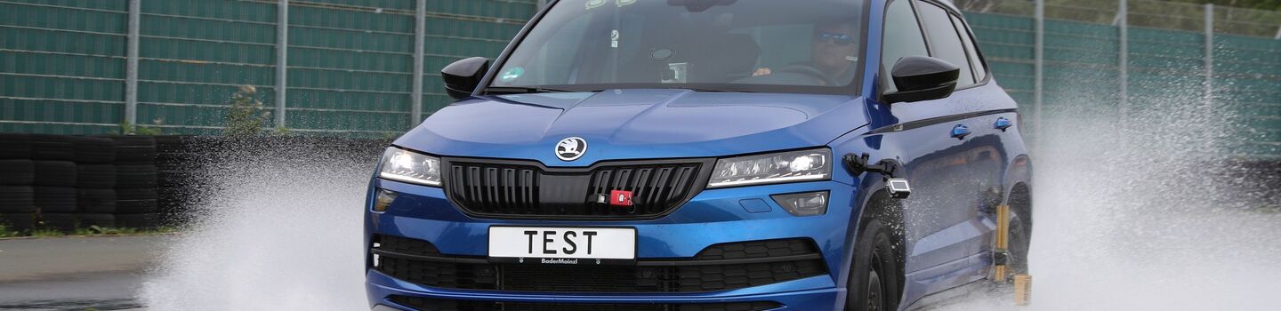 Fahrendes blaues Auto auf nasser Fahrbahn.