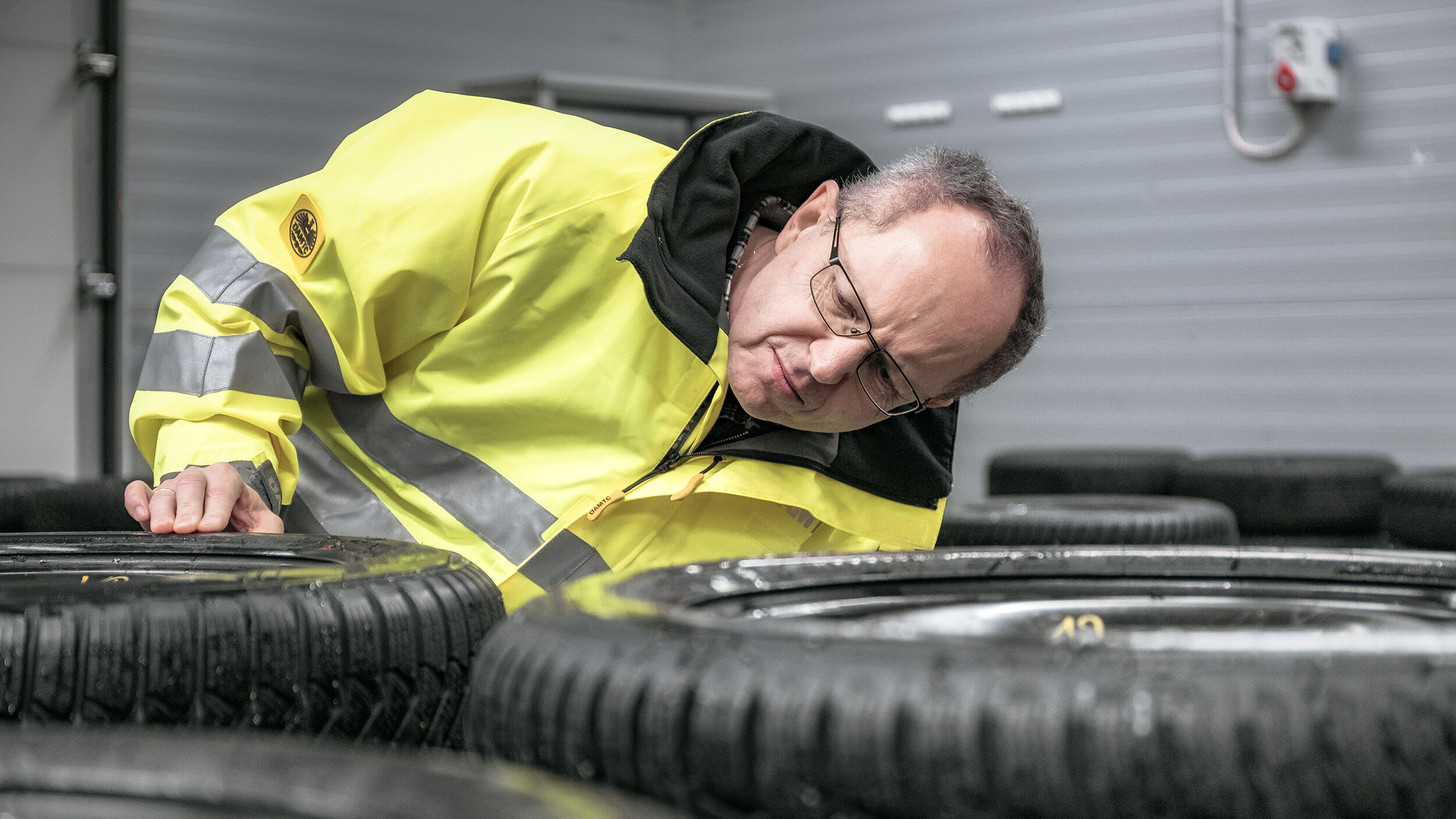 ÖAMTC-Techniker begutachtet Reifen, die flach nebeneinander liegen.