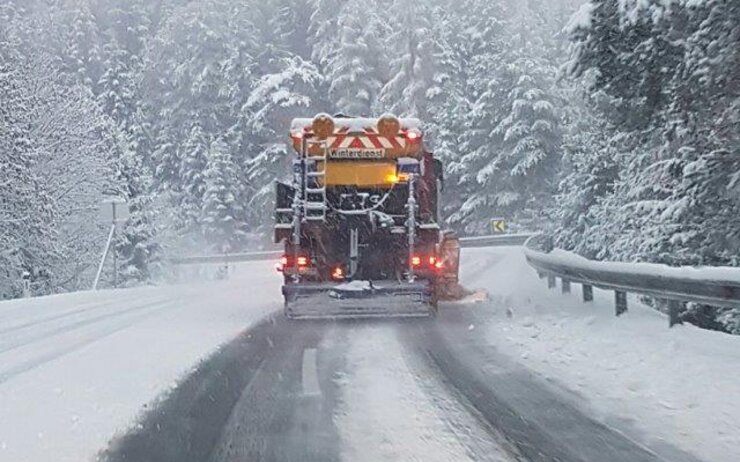 Schneepflug von hinten auf einer schneebedeckten Straße