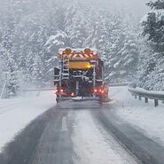 Schneepflug von hinten auf einer schneebedeckten Straße