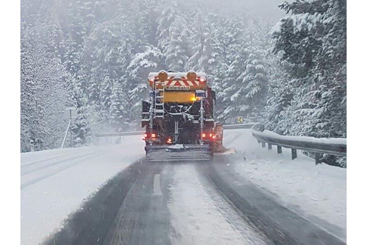 Schneepflug von hinten auf einer schneebedeckten Straße