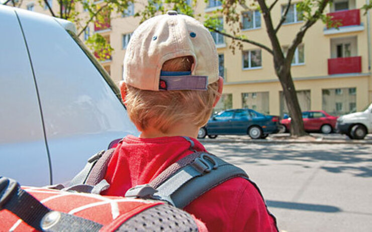 Schulweg Kind von hinten mit Schultasche beim Überqueren der Straße
