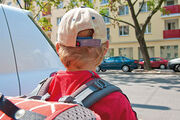 Kind von hinten mit Schultasche beim Überqueren der Straße