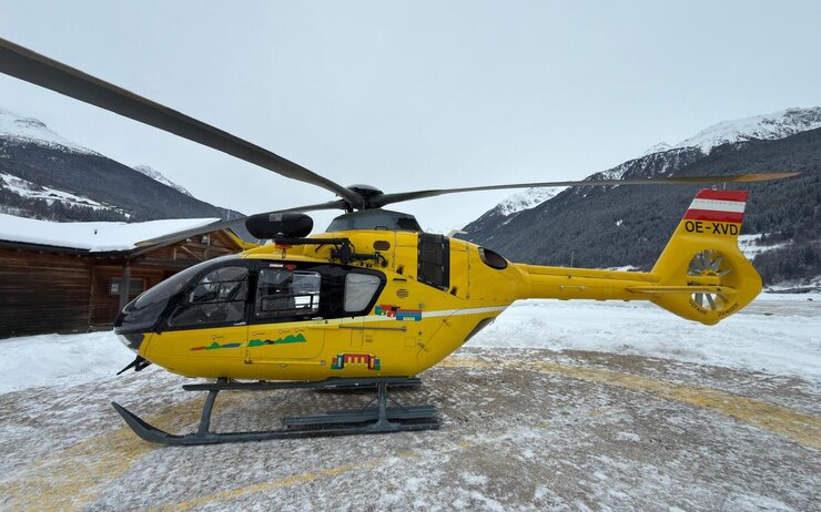 Ein gelber Notarzthubschrauber in winterlicher Landschaft.