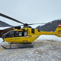 Ein gelber Notarzthubschrauber in winterlicher Landschaft.