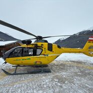 Ein gelber Notarzthubschrauber in winterlicher Landschaft.