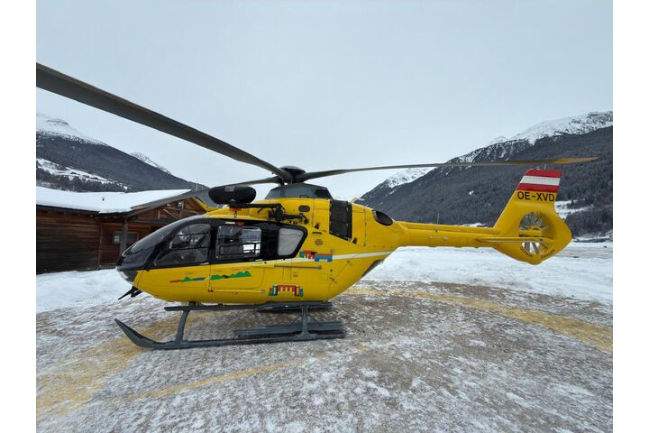 Ein gelber Notarzthubschrauber in winterlicher Landschaft.