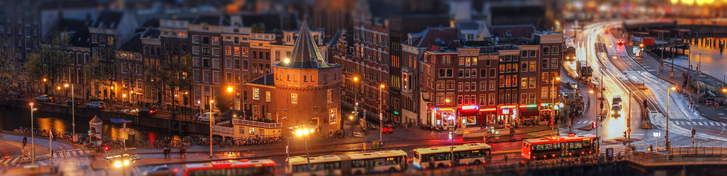 Die Nacht verwandelt Amsterdam in ein Meer von Lichtern, das die Straßen und historischen Gebäude in eine magische Atmosphäre hüllt.