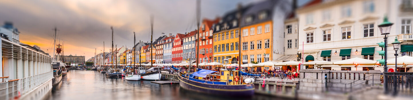 Der historische Hafen von Kopenhagen leuchtet mit seinen bunten Häusern, die lebhaft gegen den wolkenverhangenen Himmel abstechen.