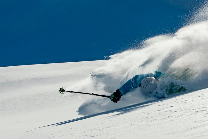 Skifahrer stürzt bei der Abfahrt auf einem verschneiten Berghang.