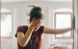 Verschwommenes Foto einer Frau, die unter Schwindel oder Benommenheit leidet, ausgelöst durch eine Erkrankung des Gehirns oder des Innenohrs.