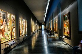 ein langer Museumsgang mit Gemälden an den Wänden
