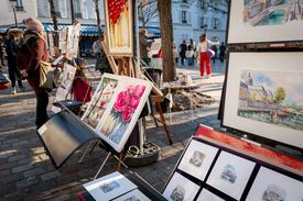 Eine Frau, die in Montmartre neben einer Staffelei mit Gemälden steht