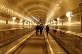 Ein langer beleuchteter Tunnel, in dem Leute gehen