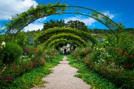 Bepflanzter Weg in Monets Gärten in Giverny, der zu einem Haus führt