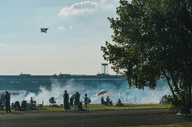 Eine Gruppe von Menschen, die auf einer Wiese grillen und Drachen steigen lassen