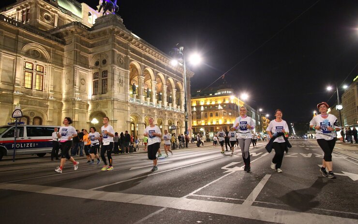 Läufer:innen und Zuschauer:innen entlang der Ringstraße am Abend.