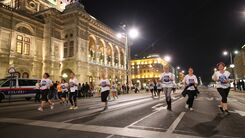 Läufer:innen und Zuschauer:innen entlang der Ringstraße am Abend.