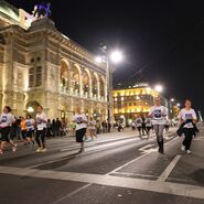Läufer:innen und Zuschauer:innen entlang der Ringstraße am Abend.