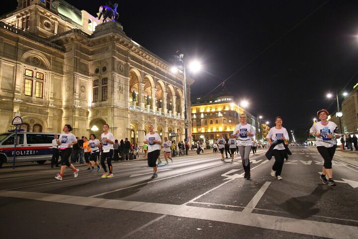 Läufer:innen und Zuschauer:innen entlang der Ringstraße am Abend.