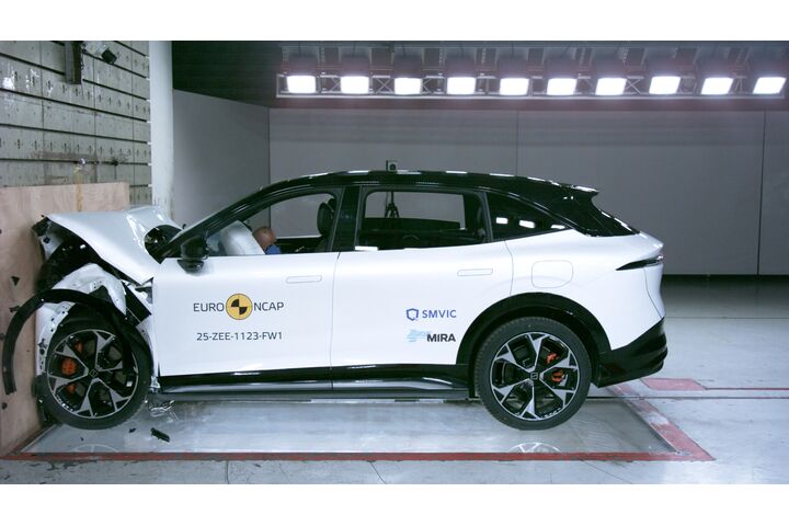 Das Foto zeigt ein weißes Auto von der Seite, das gerade im Zuge eines Crashtests frontal gegen ein Hindernis prallt.